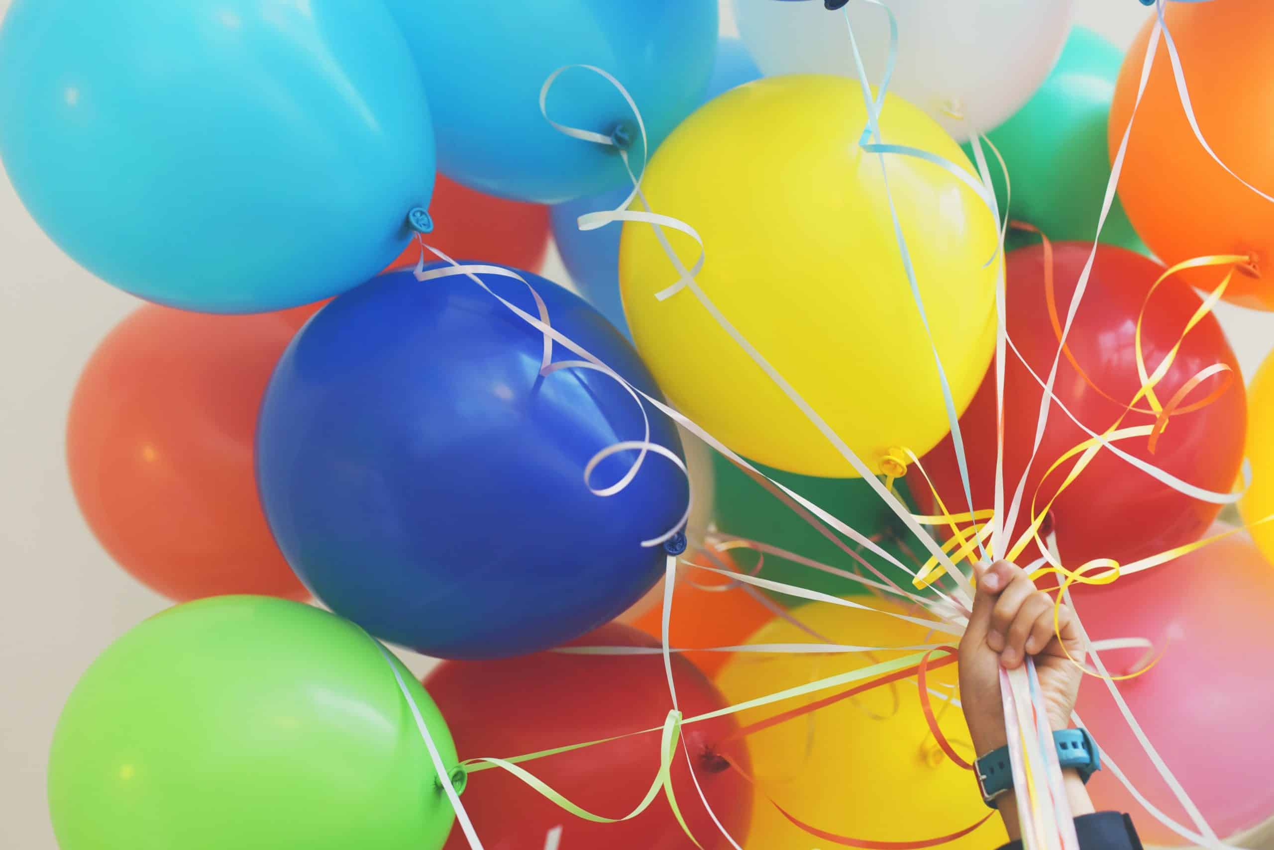 A person holding a bunch of colorful balloons.